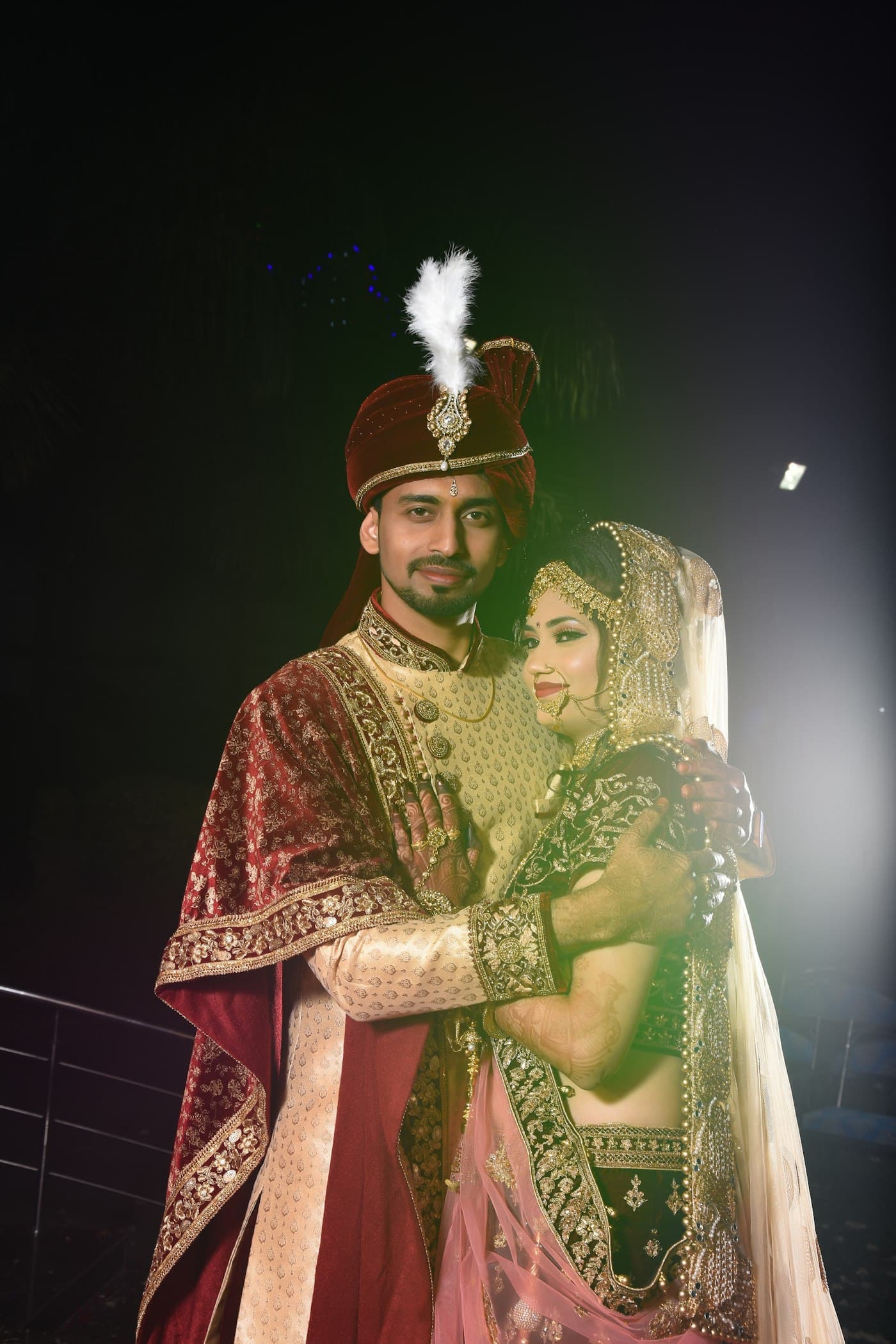 A dramatic backlit portrait of an Indian bride and groom at night