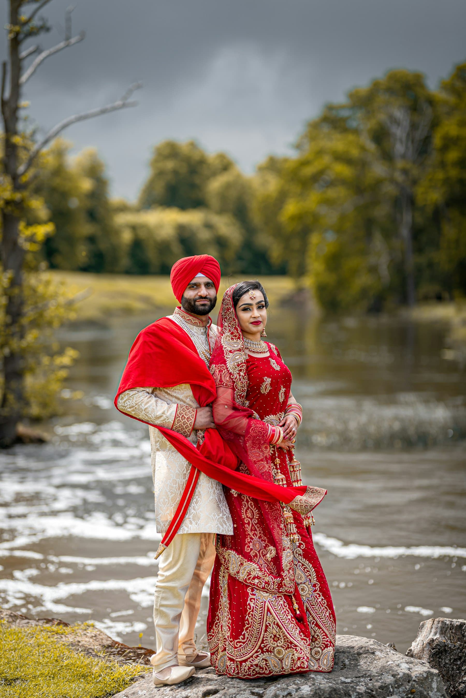 A couple in traditional Indian wedding attire standing together outdoors